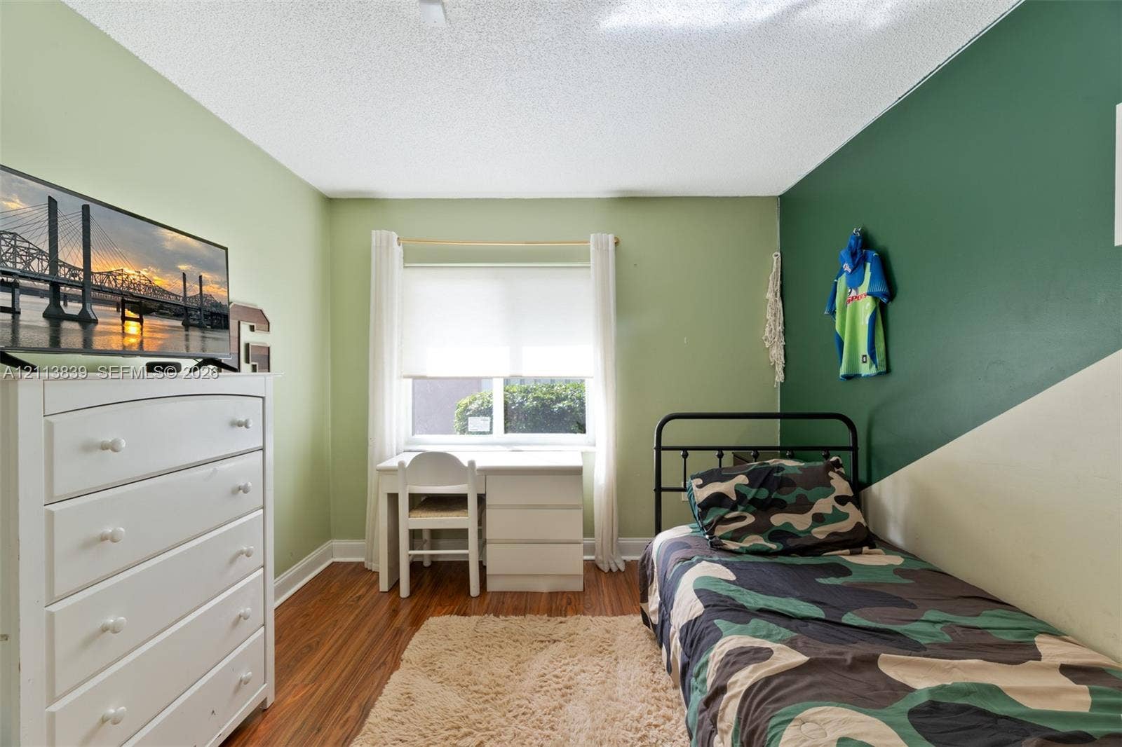 1015 NW 124th Terrace, Sunrise, FL 33323 Wood-finish flooring and dual-tone painted walls featuring a window with roller shade