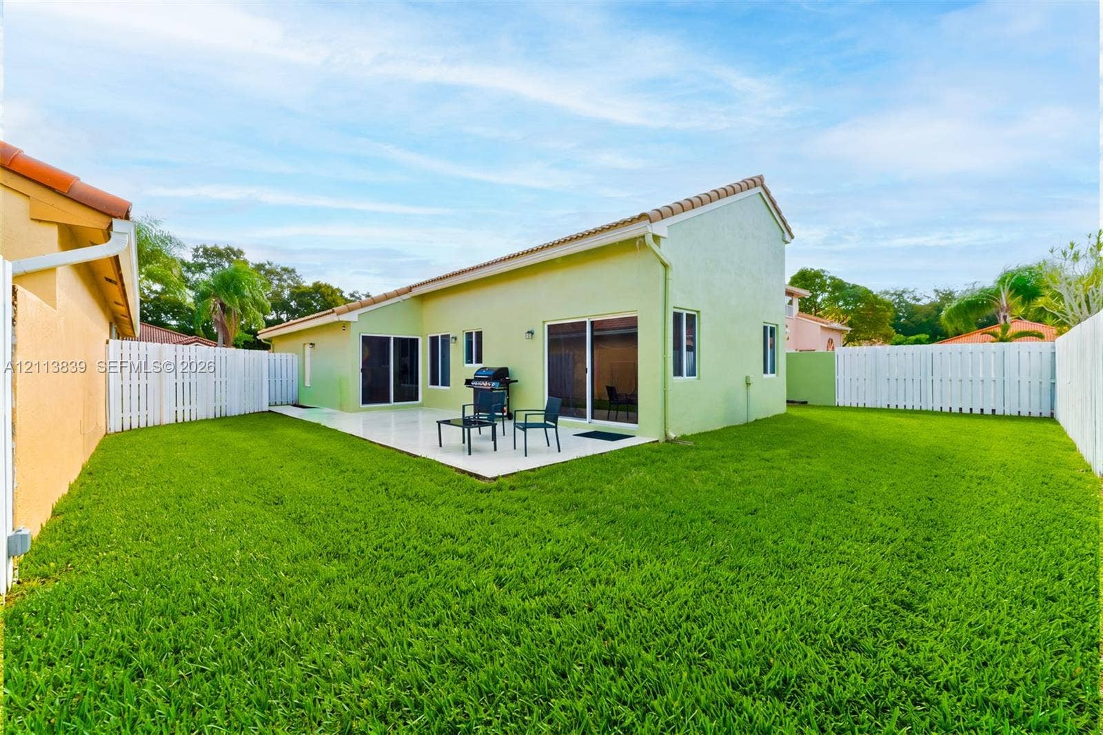1015 NW 124th Terrace, Sunrise, FL 33323 Backyard featuring a paved patio, perimeter privacy fencing, and a manicured lawn
