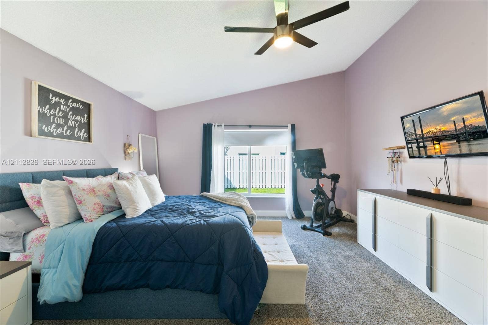 1015 NW 124th Terrace, Sunrise, FL 33323 Vaulted ceilings, neutral carpeting, ceiling fan with integrated lighting, and wall-mounted television console
