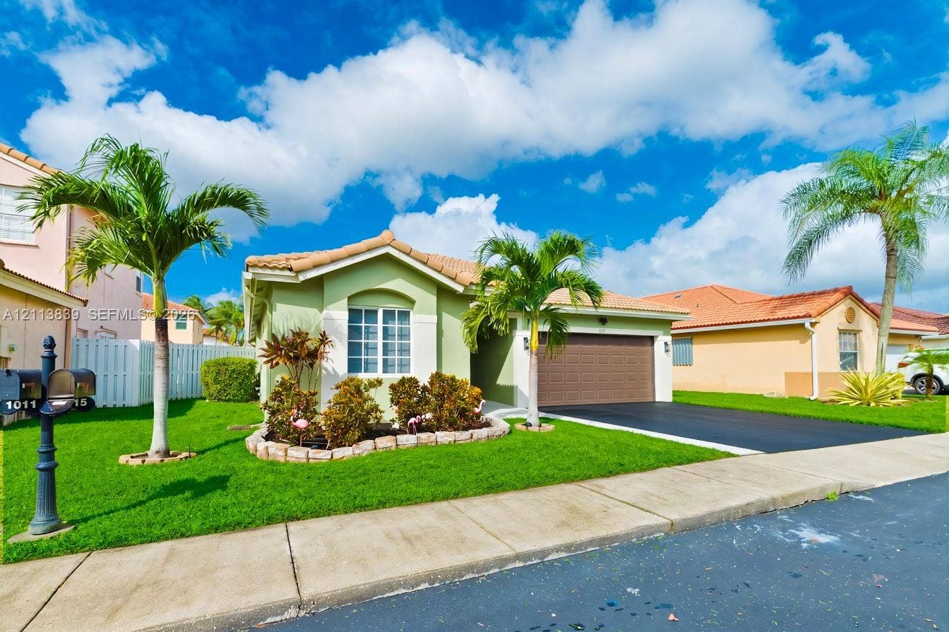 1015 NW 124th Terrace, Sunrise, FL 33323 Single-story stucco exterior featuring a tile roof, two-car garage, manicured lawn, and stone-bordered landscaping beds