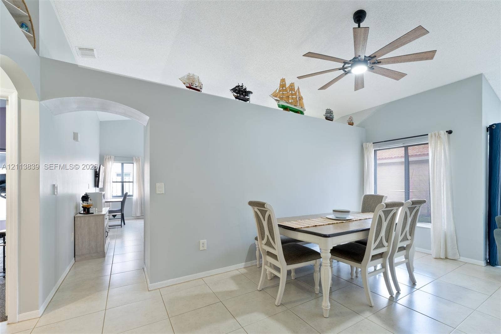1015 NW 124th Terrace, Sunrise, FL 33323 Vaulted ceilings, large-format tile flooring, arched architectural detail, multi-blade ceiling fan with integrated lighting, and sliding glass door