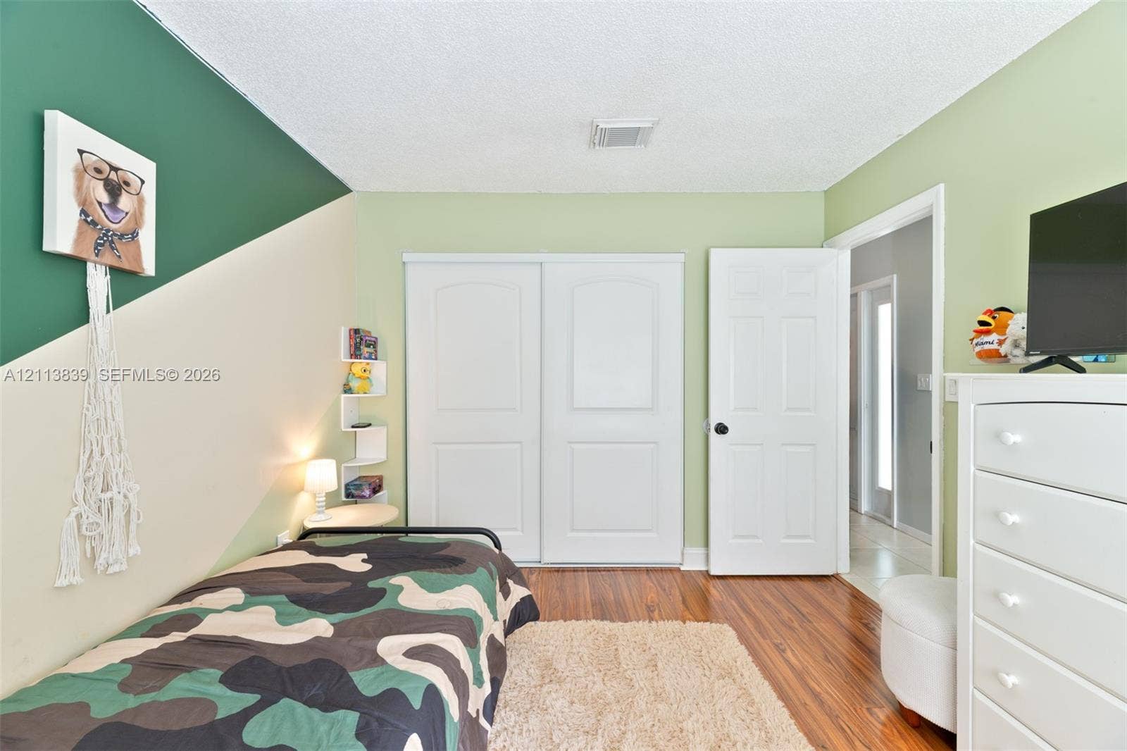 1015 NW 124th Terrace, Sunrise, FL 33323 Wood-finish flooring, dual sliding closet doors with raised panels, built-in corner shelving, and a six-panel interior door