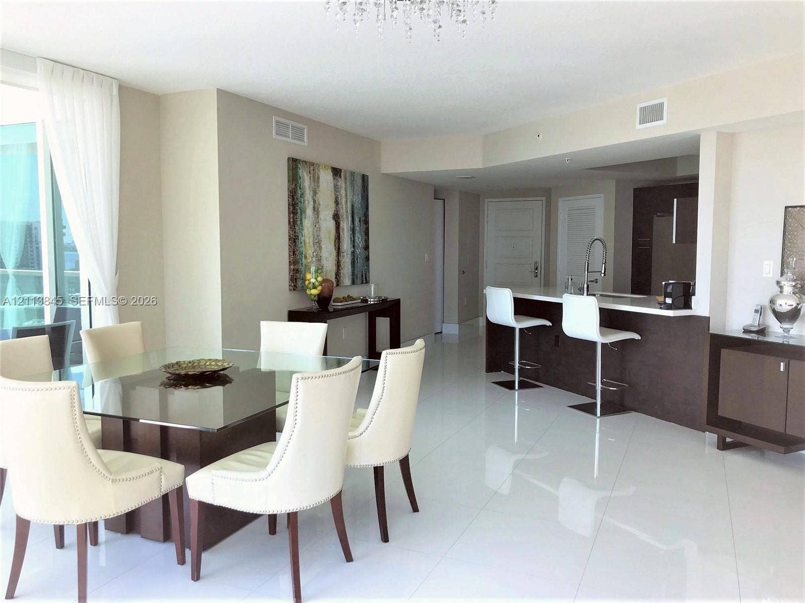 250 Sunny Isles Boulevard, #3-1506, Sunny Isles Beach, Sunny Isles Beach, FL 33160 Open-concept living space featuring high-gloss tile flooring, crystal chandelier, kitchen with breakfast bar, dark-finish cabinetry, and floor-to-ceiling glass sliding doors