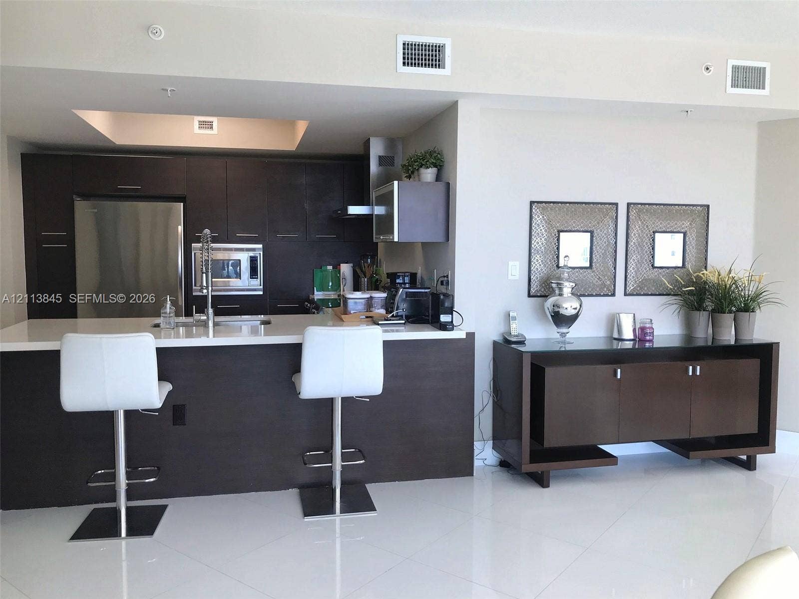 250 Sunny Isles Boulevard, #3-1506, Sunny Isles Beach, Sunny Isles Beach, FL 33160 Kitchen featuring dark wood-finish cabinetry, white solid-surface countertops, integrated stainless steel appliances, and tile flooring
