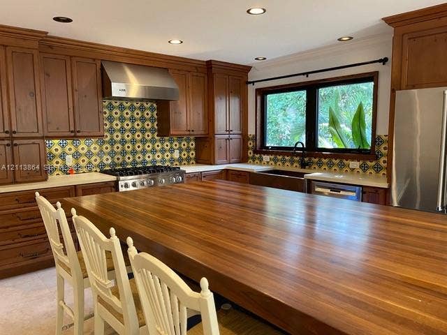 721 Tibidabo Avenue, #0, Coral Gables, Coral Gables, FL 33143 Kitchen featuring custom wood cabinetry, a large wood-topped center island, patterned tile backsplash, stainless steel range with a matching vent hood, and a deep apron-front sink