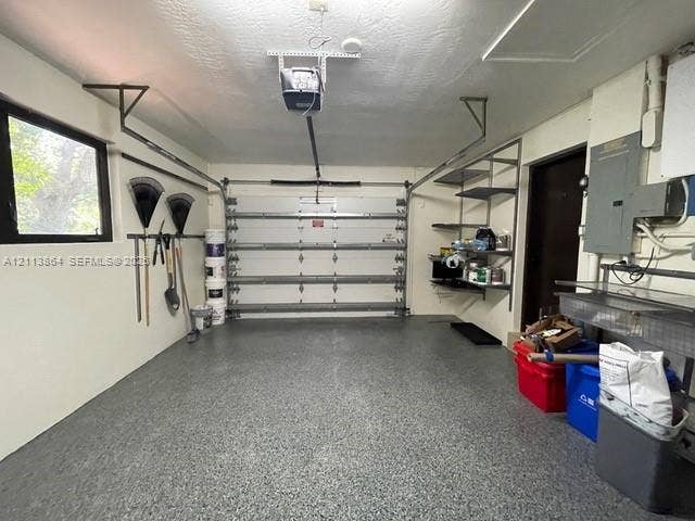 721 Tibidabo Avenue, #0, Coral Gables, Coral Gables, FL 33143 Garage featuring epoxy-coated flooring, wall-mounted metal shelving, tool storage rails, and an automated overhead door
