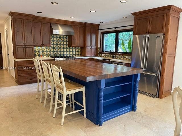 721 Tibidabo Avenue, #0, Coral Gables, Coral Gables, FL 33143 Kitchen featuring natural wood cabinetry, a central island with a wood countertop and open shelving, patterned tile backsplash, stainless steel appliances, and tile flooring