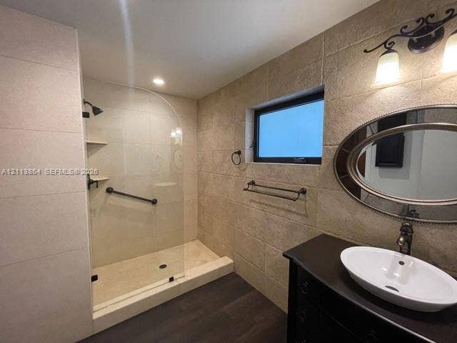 721 Tibidabo Avenue, #0, Coral Gables, Coral Gables, FL 33143 Walk-in shower with a glass enclosure, textured stone-tile wall, wood-finish flooring, oval vanity mirror, and vessel sink with an oil-rubbed bronze faucet