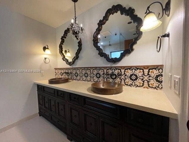 721 Tibidabo Avenue, #0, Coral Gables, Coral Gables, FL 33143 Double vanity featuring dark wood cabinetry, a solid surface countertop, dual vessel sinks, decorative patterned tile backsplash, and ornate wall-mounted mirrors