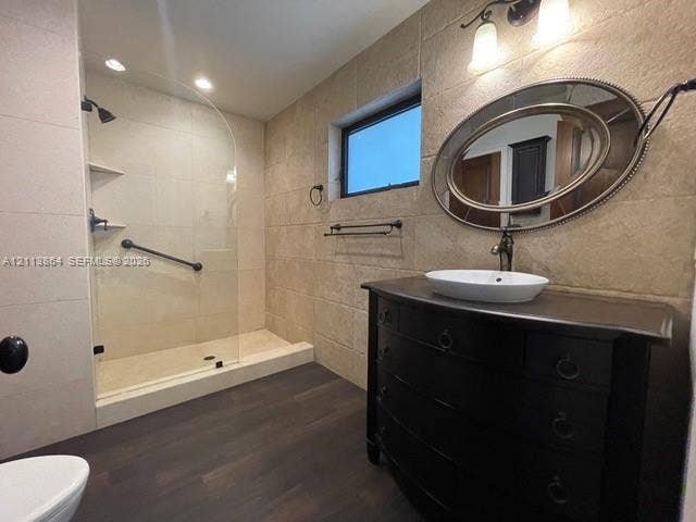 721 Tibidabo Avenue, #0, Coral Gables, Coral Gables, FL 33143 Bathroom featuring wood-finish flooring, textured stone-style wall tile, a glass-enclosed walk-in shower with integrated shelving, and a dark-toned vanity cabinet topped with a vessel sink