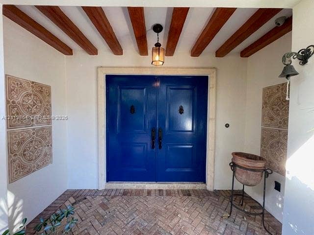 721 Tibidabo Avenue, #0, Coral Gables, Coral Gables, FL 33143 Entryway featuring double solid-panel doors with iron knockers, exposed wood ceiling beams, decorative wall tile accents, and herringbone-patterned brick flooring