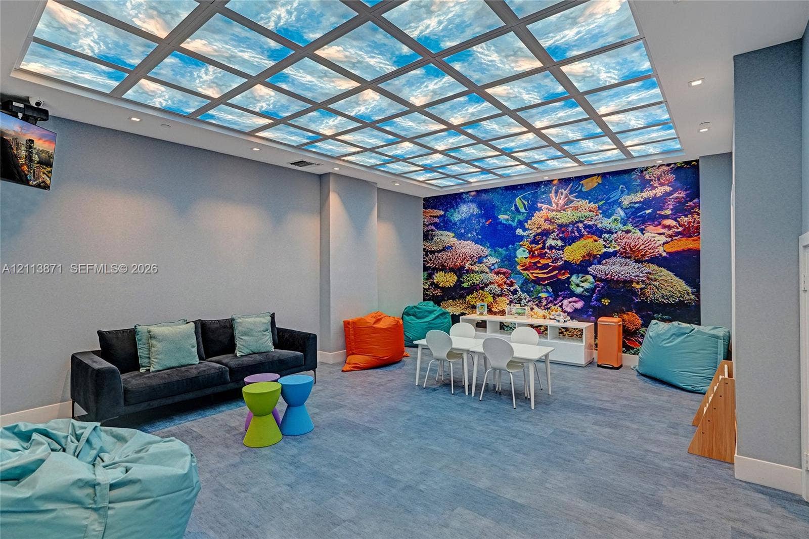 3640 Yacht Club Drive, #1208, Aventura, FL 33180 Customized grid ceiling panel with sky-pattern graphic, large-scale coral reef wall mural, recessed ceiling lighting, and blue-toned flooring