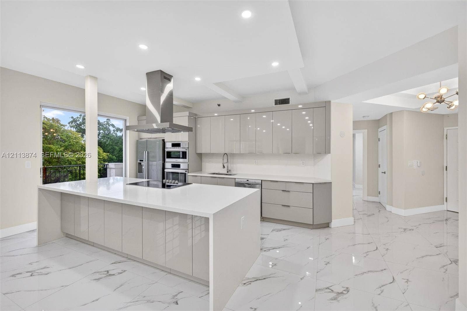 3900 Island Boulevard, #B408, Aventura, Aventura, FL 33160 Contemporary kitchen featuring high-gloss cabinetry, a waterfall-edge island with a stone-finish countertop, stainless steel appliances, and large-format porcelain tile flooring
