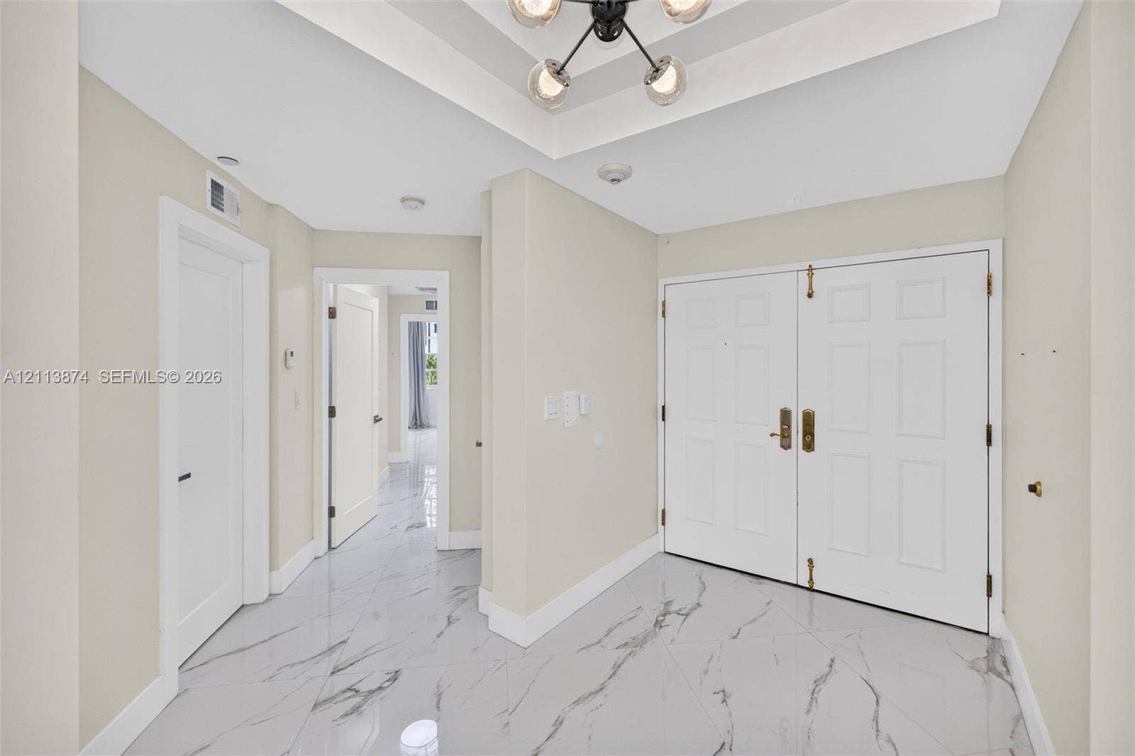 3900 Island Boulevard, #B408, Aventura, Aventura, FL 33160 Foyer featuring large-format stone-look tile flooring, a tray ceiling, and a multi-arm pendant light fixture