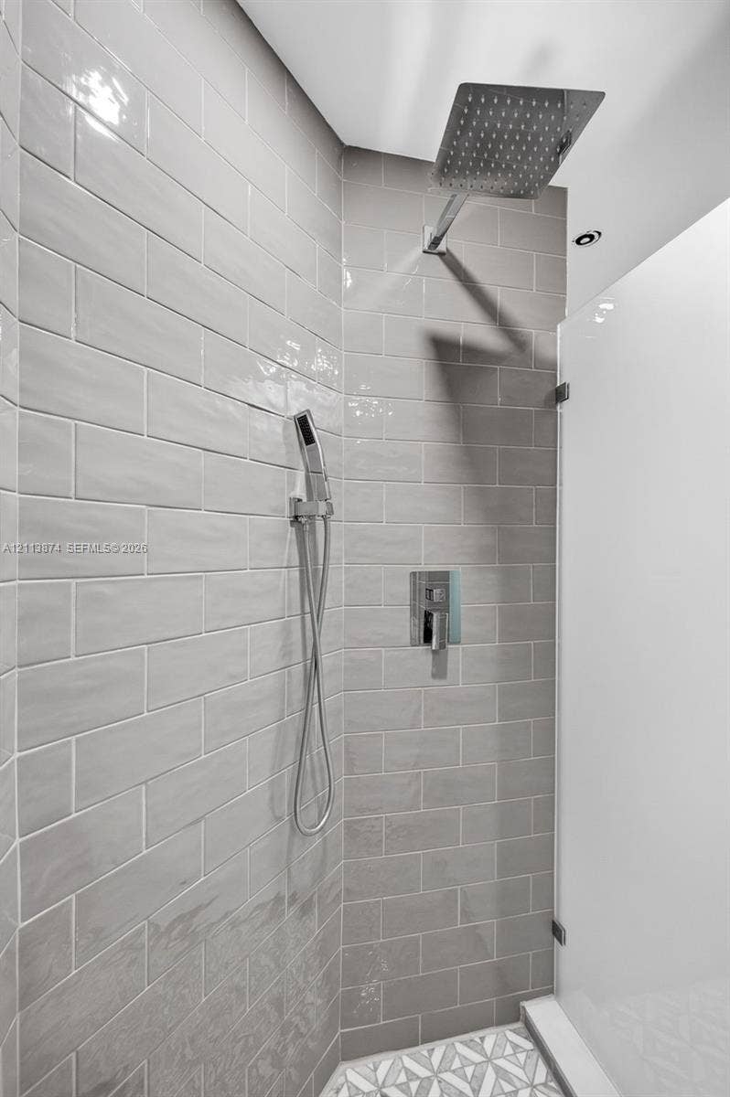 3900 Island Boulevard, #B408, Aventura, Aventura, FL 33160 Walk-in shower featuring light grey subway tile, square overhead rainfall fixture, detachable handheld sprayer, polished chrome hardware, and geometric patterned floor tiling
