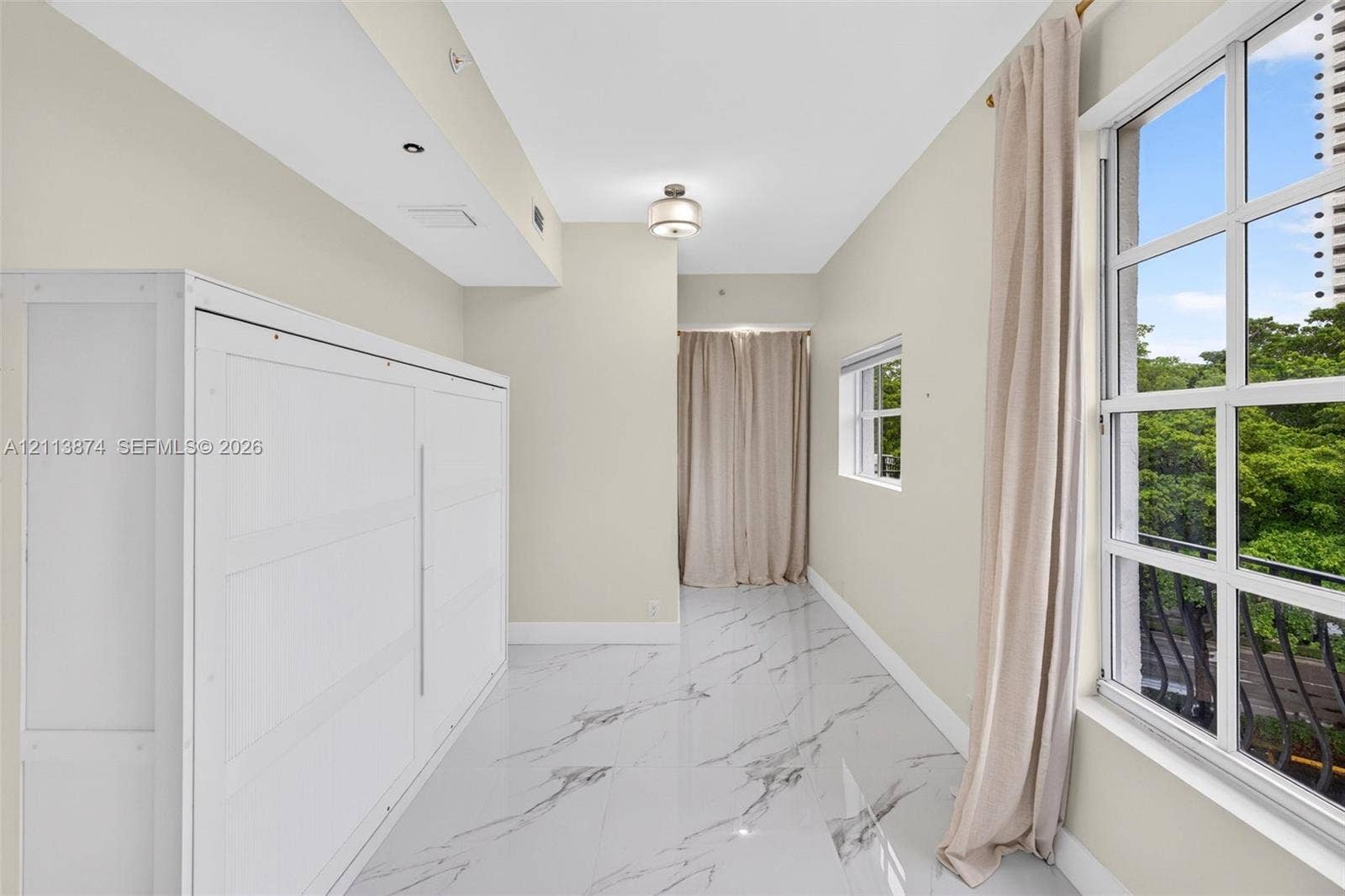 3900 Island Boulevard, #B408, Aventura, Aventura, FL 33160 Polished stone-finish flooring with veining detail, integrated white cabinetry, grid-pane windows, and a flush-mount ceiling fixture