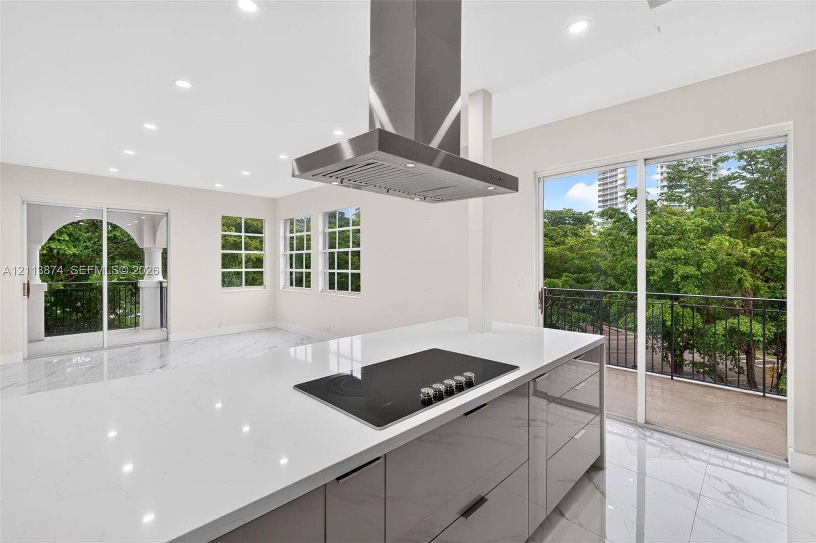 3900 Island Boulevard, #B408, Aventura, Aventura, FL 33160 Kitchen featuring a central island with a quartz countertop, integrated electric cooktop, stainless steel chimney-style range hood, gloss-finish cabinetry, and large-format porcelain tile flooring