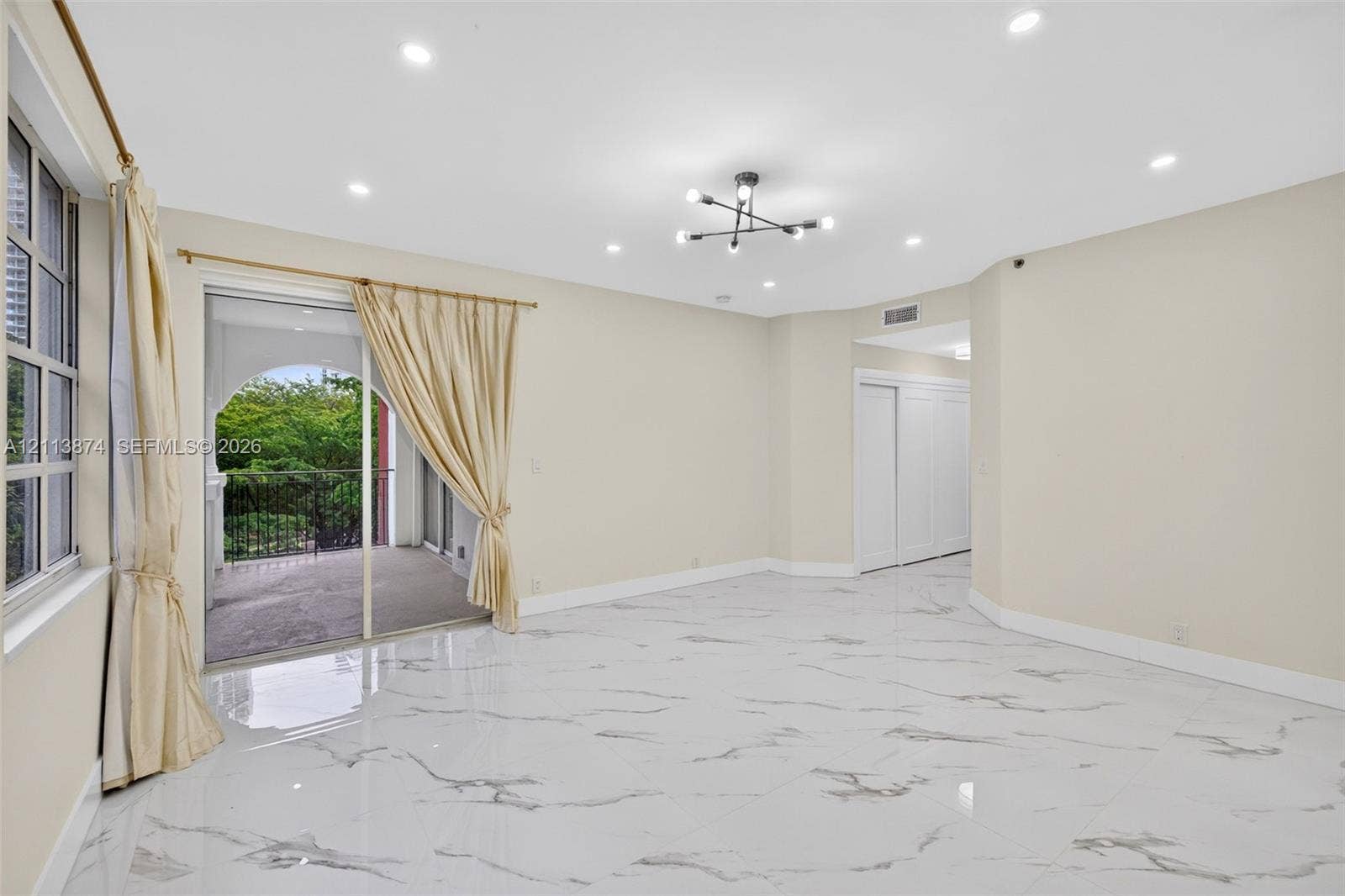 3900 Island Boulevard, #B408, Aventura, Aventura, FL 33160 Large format stone-finish tile flooring, multi-arm geometric ceiling light fixture, recessed lighting, sliding glass door, and covered balcony with metal railing