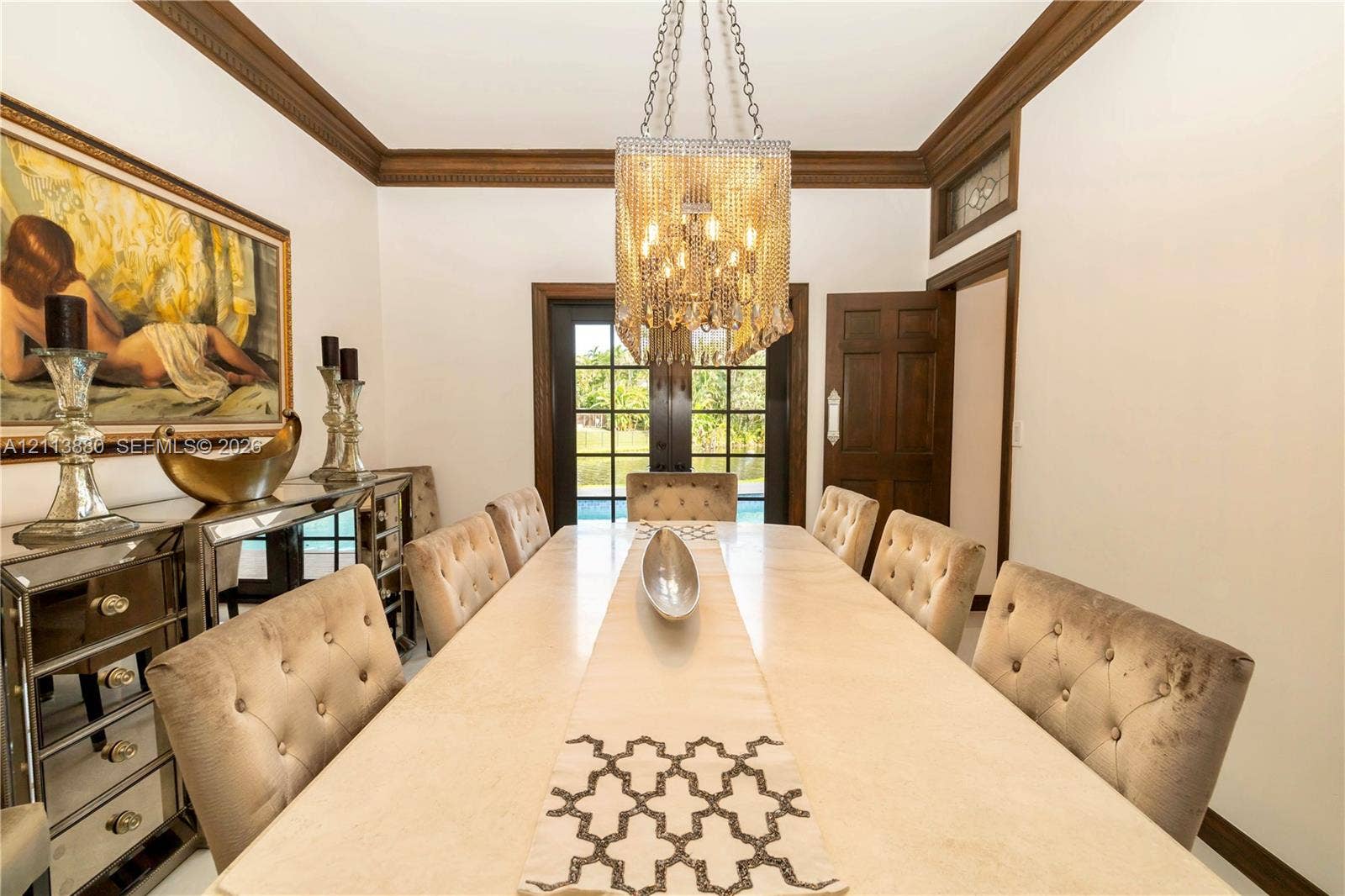 900 Coco Plum Way, Plantation, FL 33324 Formal dining area featuring rich wood crown molding, multi-pane glass exterior doors, and a decorative crystal-style chandelier