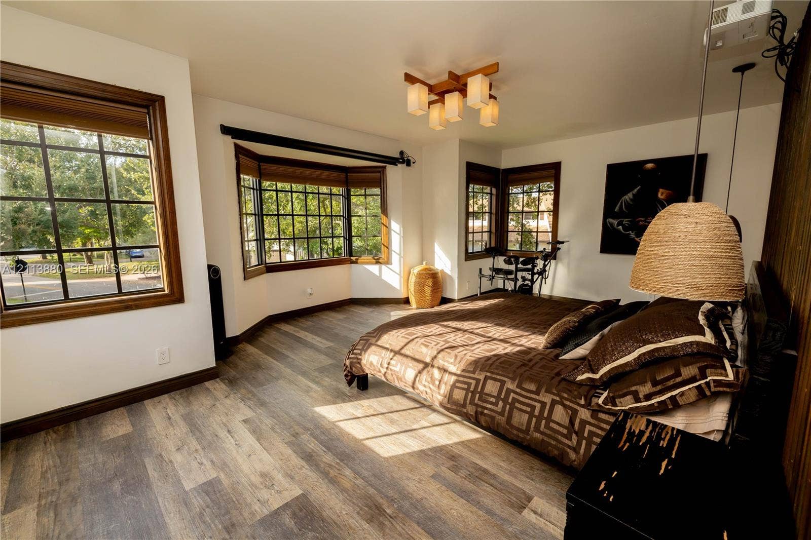 900 Coco Plum Way, Plantation, FL 33324 Wood-finish flooring, multi-pane windows with wood-tone casing, bay window, geometric-style multi-light ceiling fixture, and wood-paneled accent wall