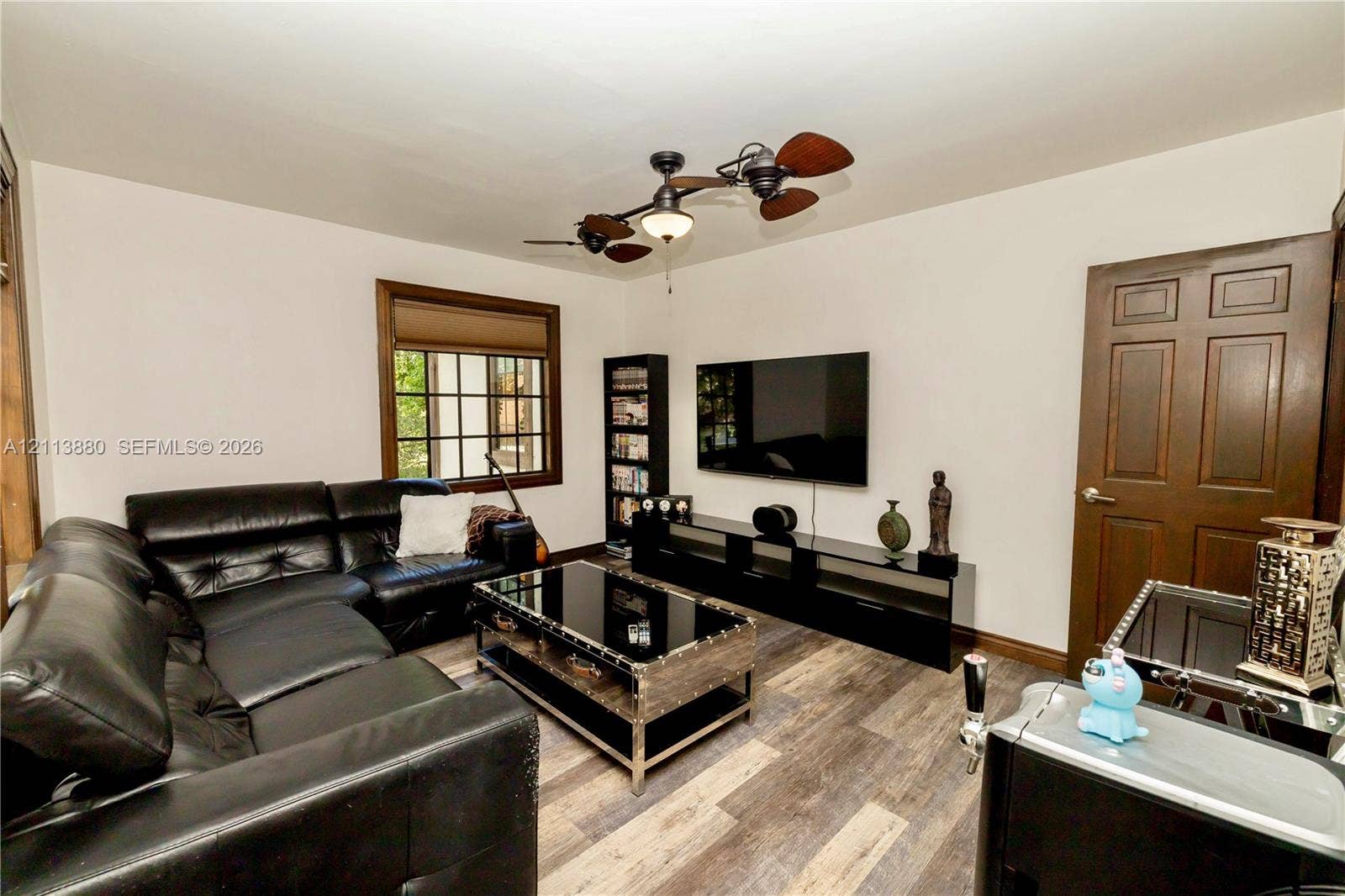 900 Coco Plum Way, Plantation, FL 33324 Multi-tonal wood-finish flooring, dark-stained six-panel door, multi-pane window with dark-stained trim, and multi-blade ceiling fan with integrated lighting