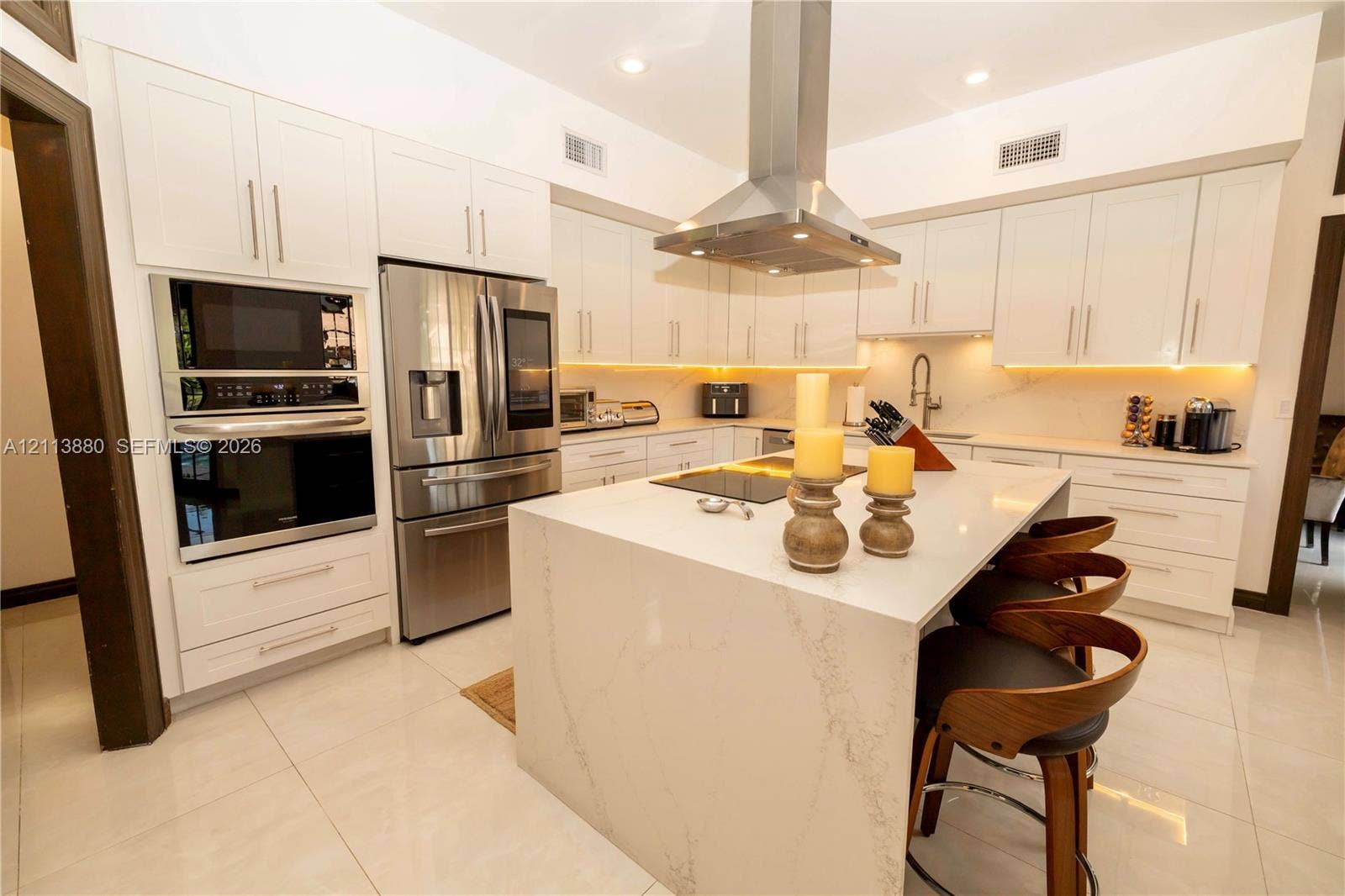 900 Coco Plum Way, Plantation, FL 33324 Kitchen featuring white cabinetry, quartz countertops with a waterfall edge island, stainless steel wall-mounted range hood, built-in stainless steel double oven, and integrated cabinet lighting