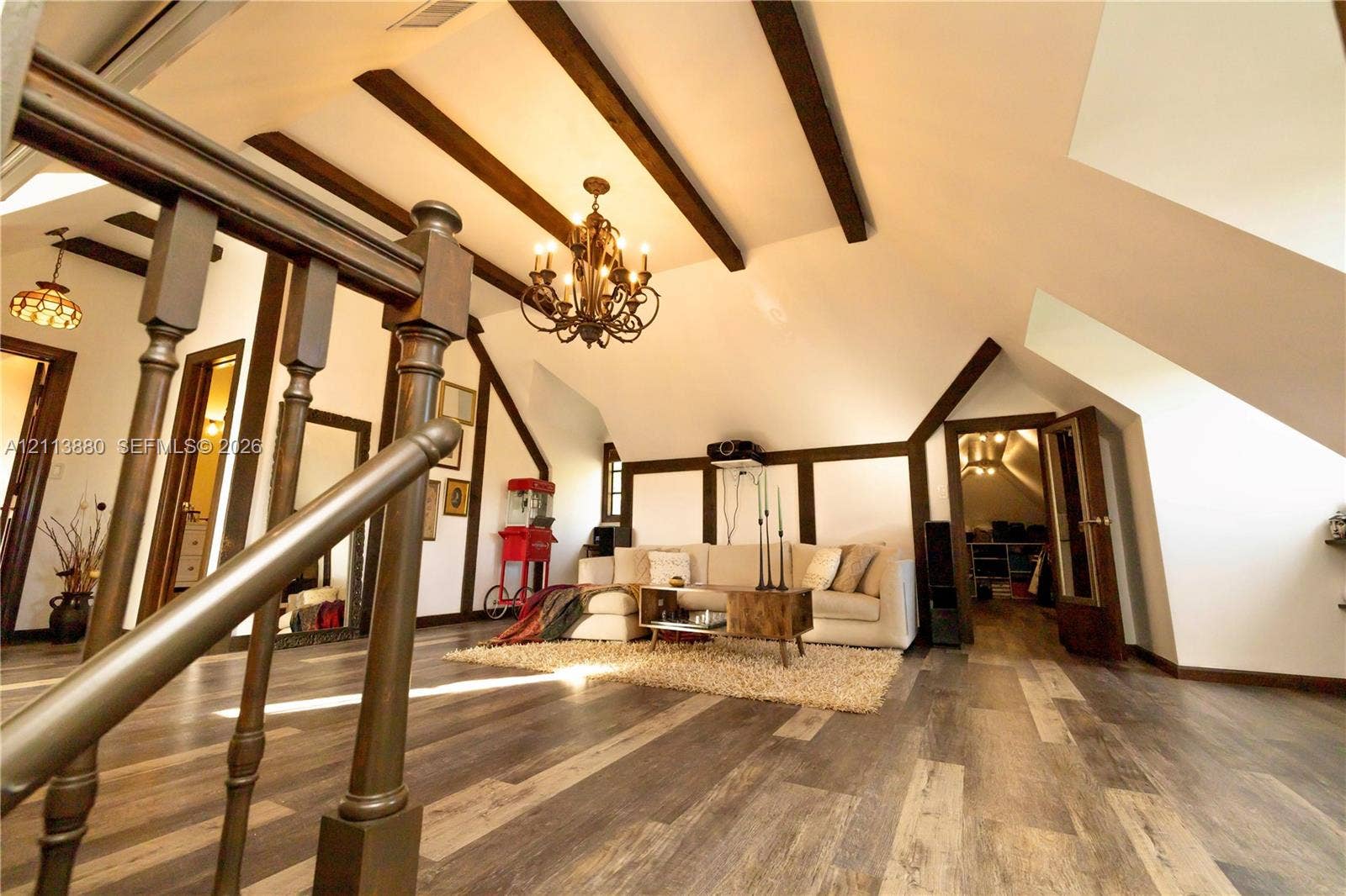 900 Coco Plum Way, Plantation, FL 33324 Vaulted ceiling featuring exposed dark wood beams, wood-finish flooring, decorative wood trim, and a multi-arm iron chandelier