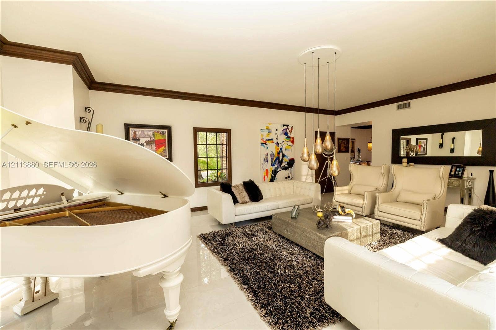 900 Coco Plum Way, Plantation, FL 33324 Spacious living area featuring polished tile flooring, prominent crown molding, multi-pendant tiered lighting, and large-paned windows with dark wood trim