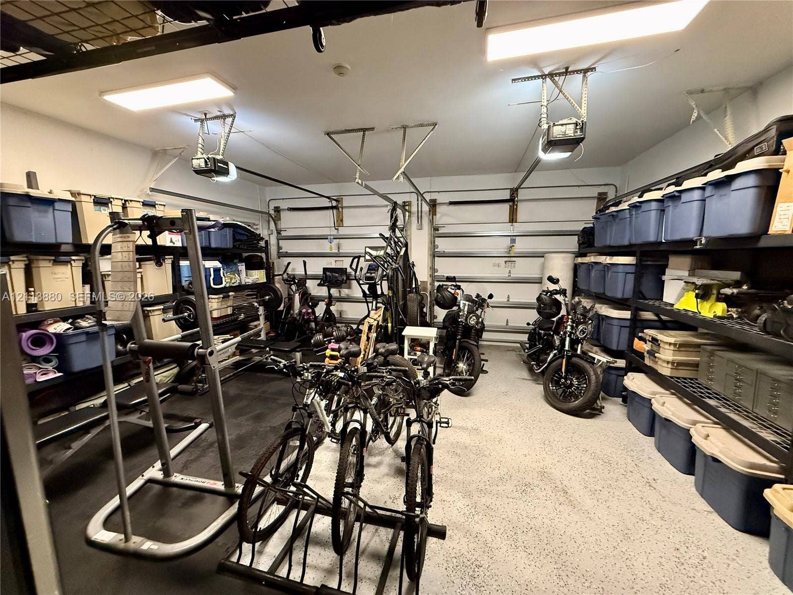 900 Coco Plum Way, Plantation, FL 33324 Two-car garage featuring epoxy-coated flooring, dual automatic door openers, and wall-mounted metal shelving units