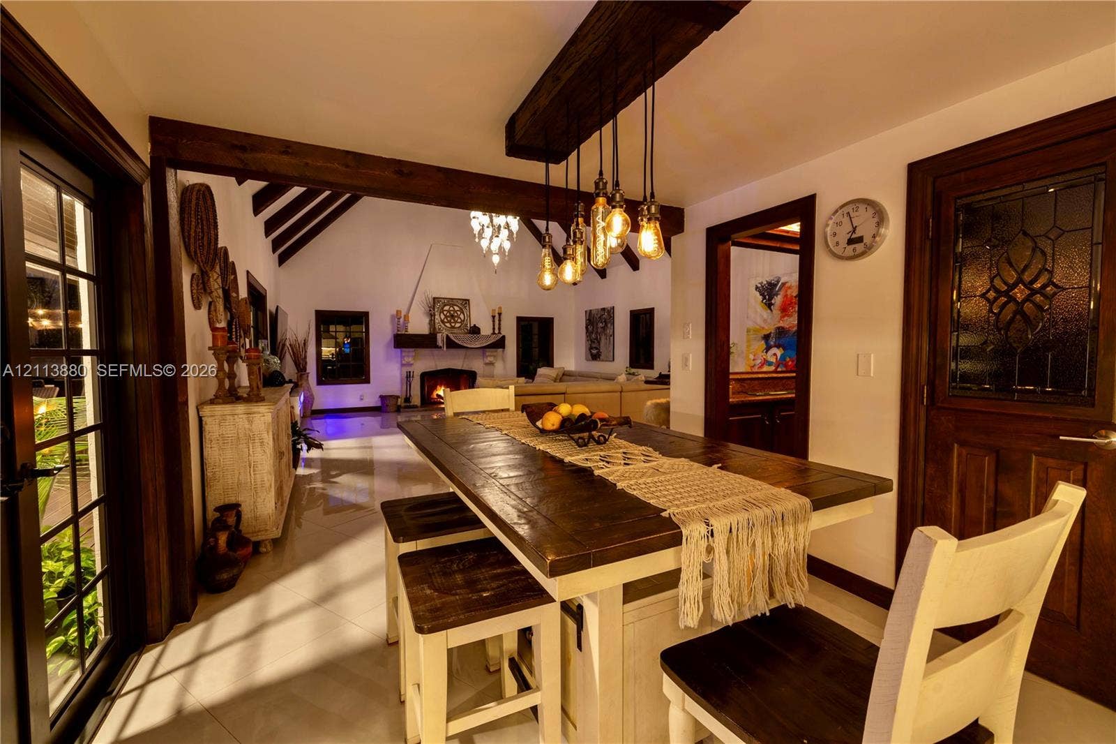 900 Coco Plum Way, Plantation, FL 33324 Dining area featuring exposed wooden ceiling beams, a custom multi-bulb pendant fixture, tile flooring, and a door with decorative glass inlay
