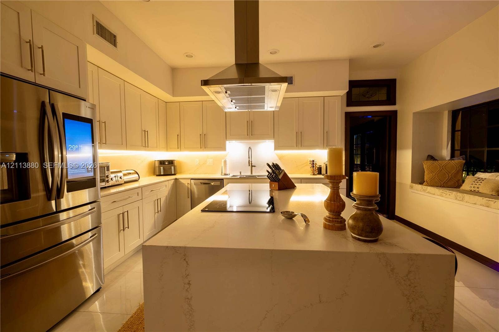 900 Coco Plum Way, Plantation, FL 33324 Kitchen featuring white cabinetry, an expansive center island with stone-finish countertops, stainless steel appliances, a ceiling-mounted range hood, and integrated under-cabinet lighting