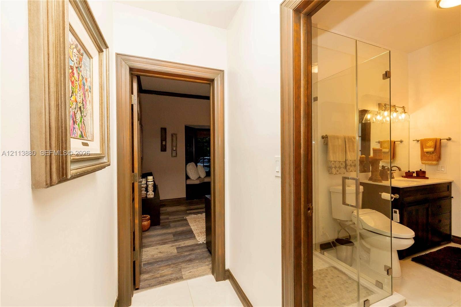 900 Coco Plum Way, Plantation, FL 33324 Bathroom featuring a dark wood vanity with a light-toned countertop, a glass-enclosed shower, and a ceramic toilet, framed by wood-trimmed doorways