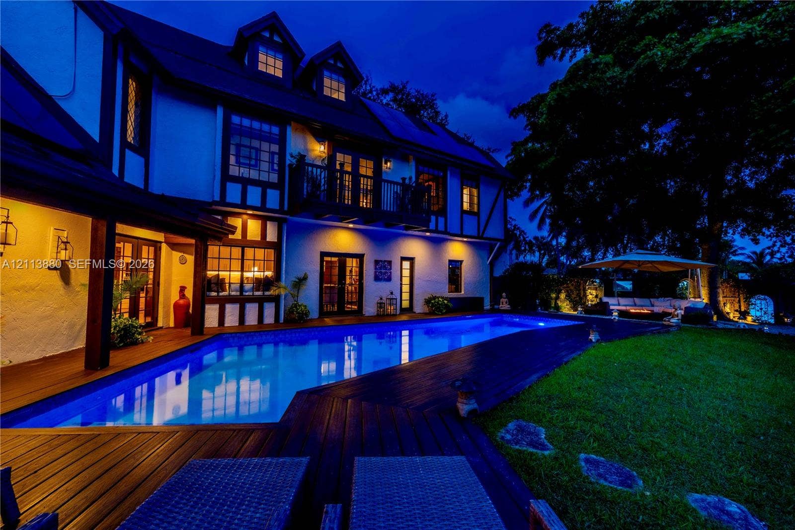 900 Coco Plum Way, Plantation, FL 33324 Tudor-style exterior featuring a rectangular inground swimming pool, expansive wood-finish decking, second-story balcony, and steep-pitched roofline with dormer windows