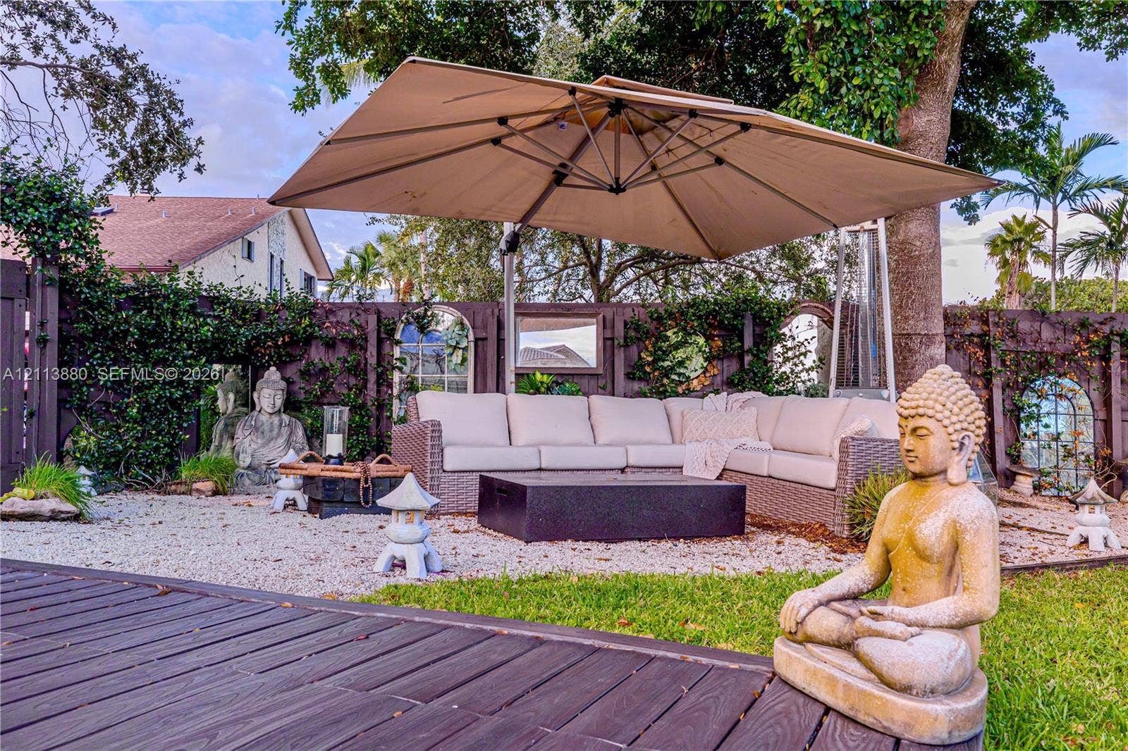 900 Coco Plum Way, Plantation, FL 33324 Outdoor living area featuring a wooden deck, crushed stone ground cover, and a dark-toned privacy fence with inset decorative mirrors