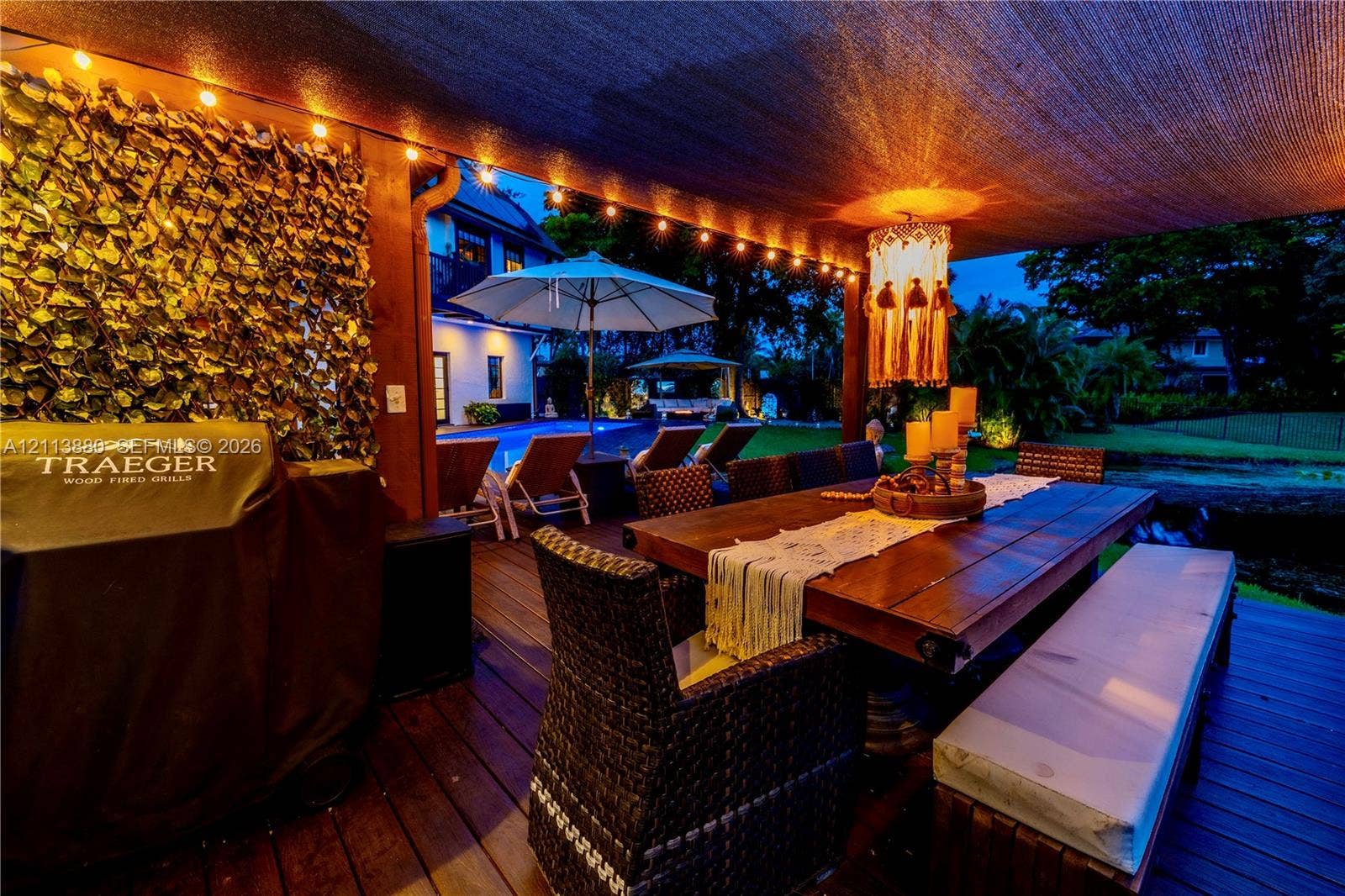 900 Coco Plum Way, Plantation, FL 33324 Covered outdoor deck featuring wood-finish decking, integrated string lighting, and a privacy screen with decorative faux foliage