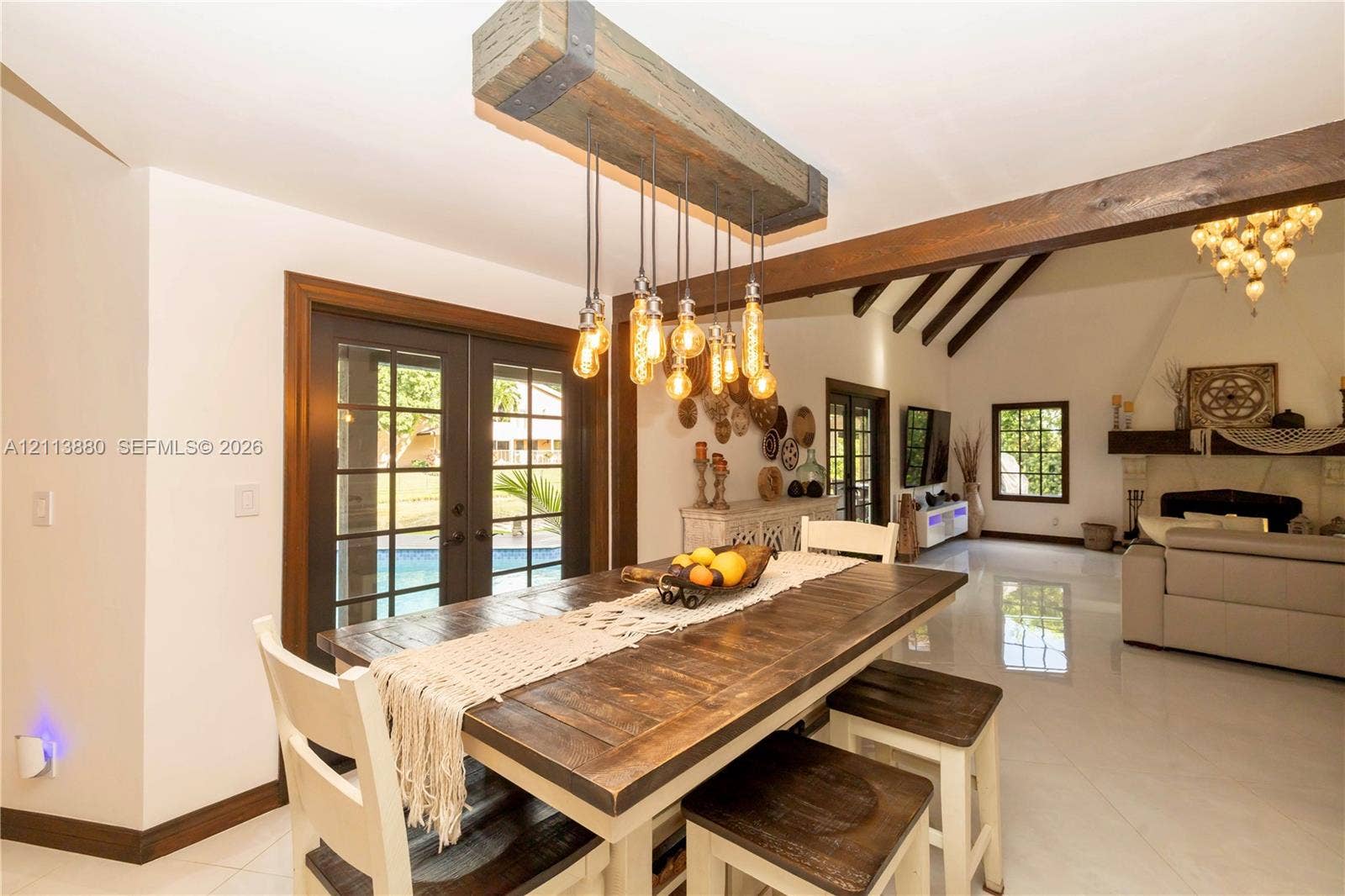 900 Coco Plum Way, Plantation, FL 33324 Custom timber beam lighting fixture with exposed filaments, dark-stained wood ceiling beams, multi-pane glass doors, and polished stone flooring