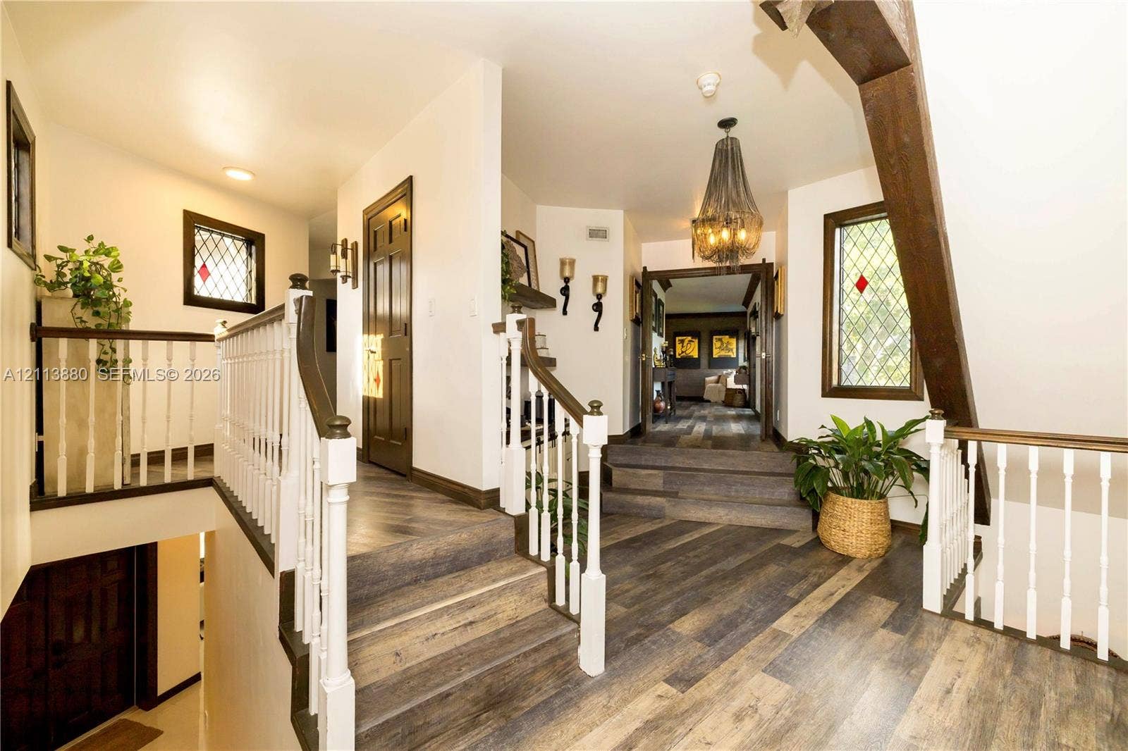 900 Coco Plum Way, Plantation, FL 33324 Foyer featuring wood-finish flooring, white spindle railings, decorative leaded glass windows, exposed structural timber beams, and a tiered staircase