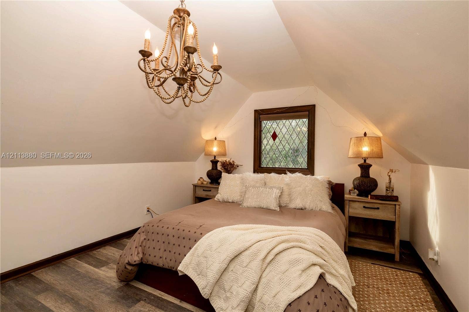900 Coco Plum Way, Plantation, FL 33324 Sloped ceiling room featuring wood-finish flooring, a decorative beaded chandelier, and a leaded glass window with a dark wood frame