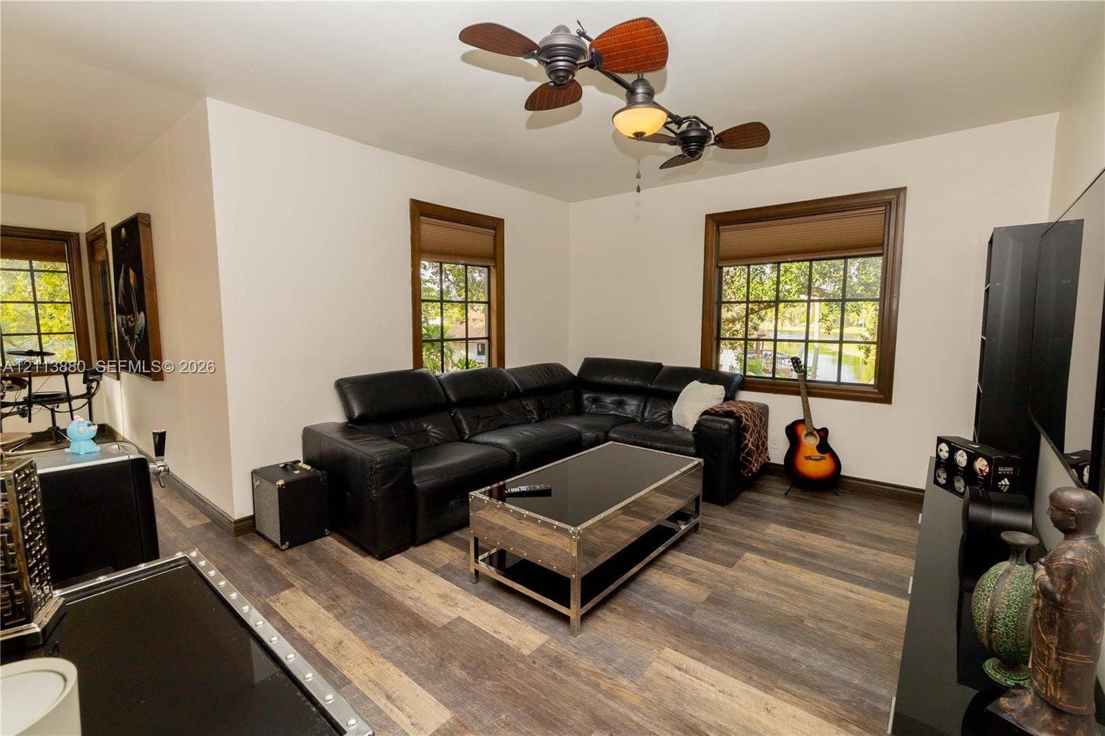 900 Coco Plum Way, Plantation, FL 33324 Wood-finish flooring, multi-pane windows with dark wood trim, and a dual-motor ceiling fan with integrated lighting