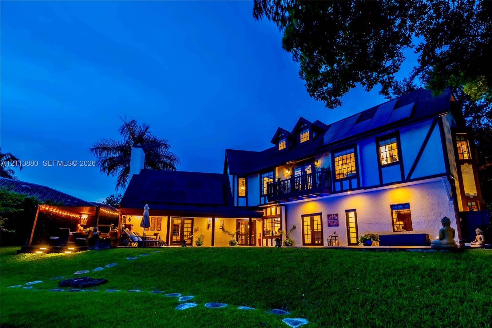 900 Coco Plum Way, Plantation, FL 33324 Two-story Tudor-style exterior featuring half-timber detailing, multiple gables, a second-story balcony with decorative railing, and integrated exterior lighting
