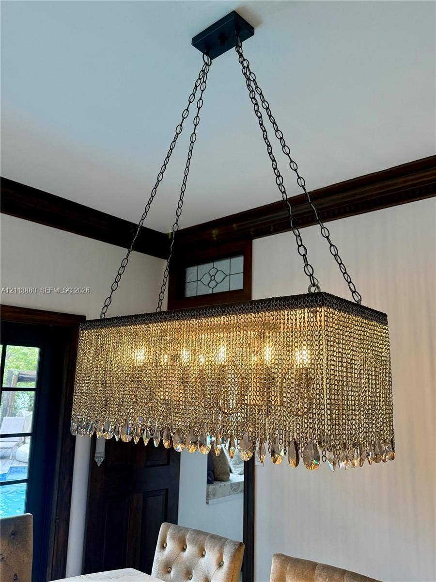 900 Coco Plum Way, Plantation, FL 33324 Rectangular chandelier featuring tiered crystal fringe, metal chain suspension, dark wood crown molding, and a transom window with leaded glass detail
