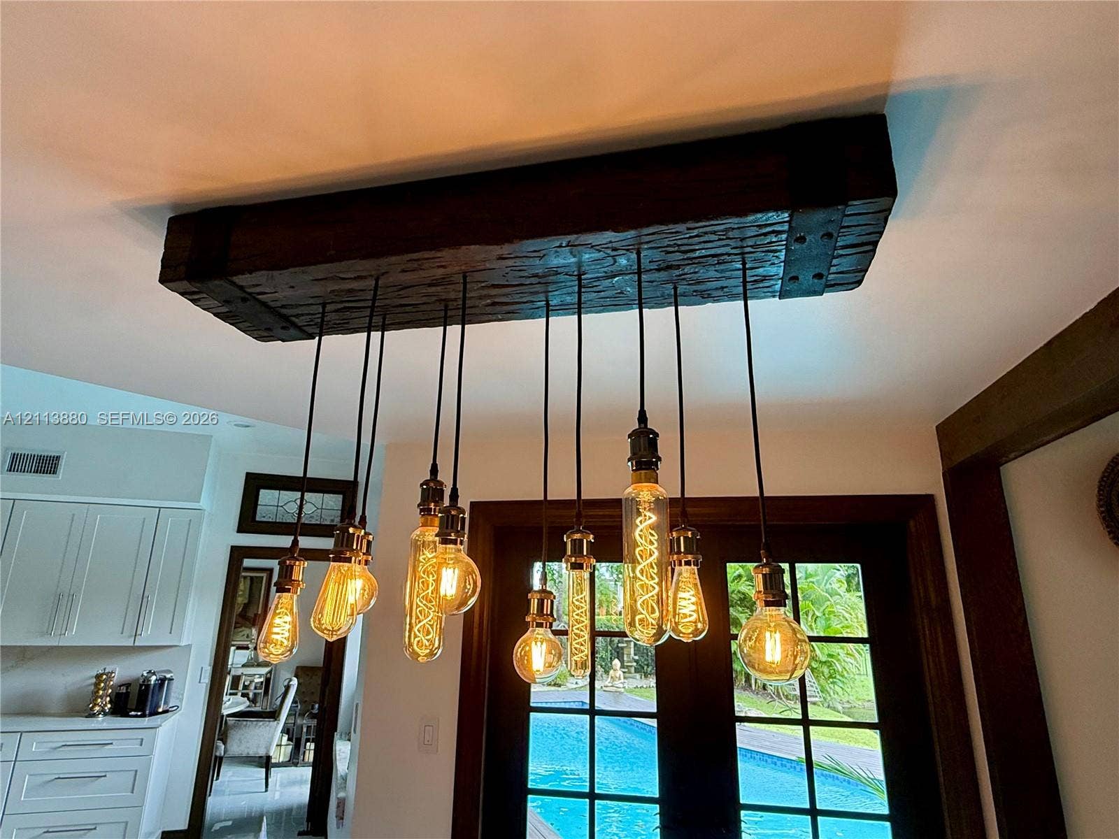 900 Coco Plum Way, Plantation, FL 33324 Custom industrial-style light fixture featuring a rustic reclaimed wood beam housing and a multi-pendant arrangement with exposed filament bulbs