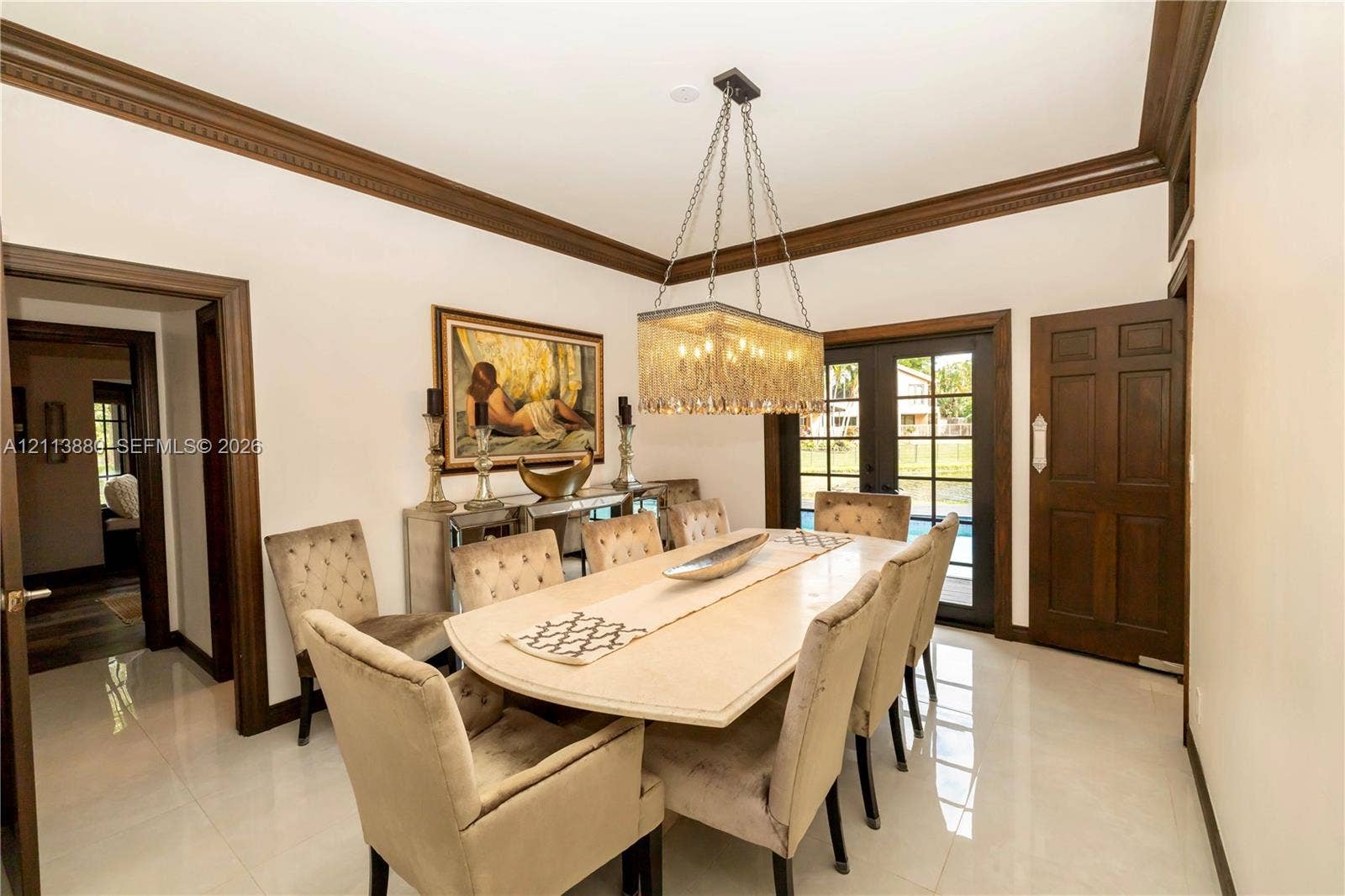 900 Coco Plum Way, Plantation, FL 33324 Dining area featuring high-gloss tile flooring, crown molding, a rectangular tiered crystal chandelier, and a six-panel wood door