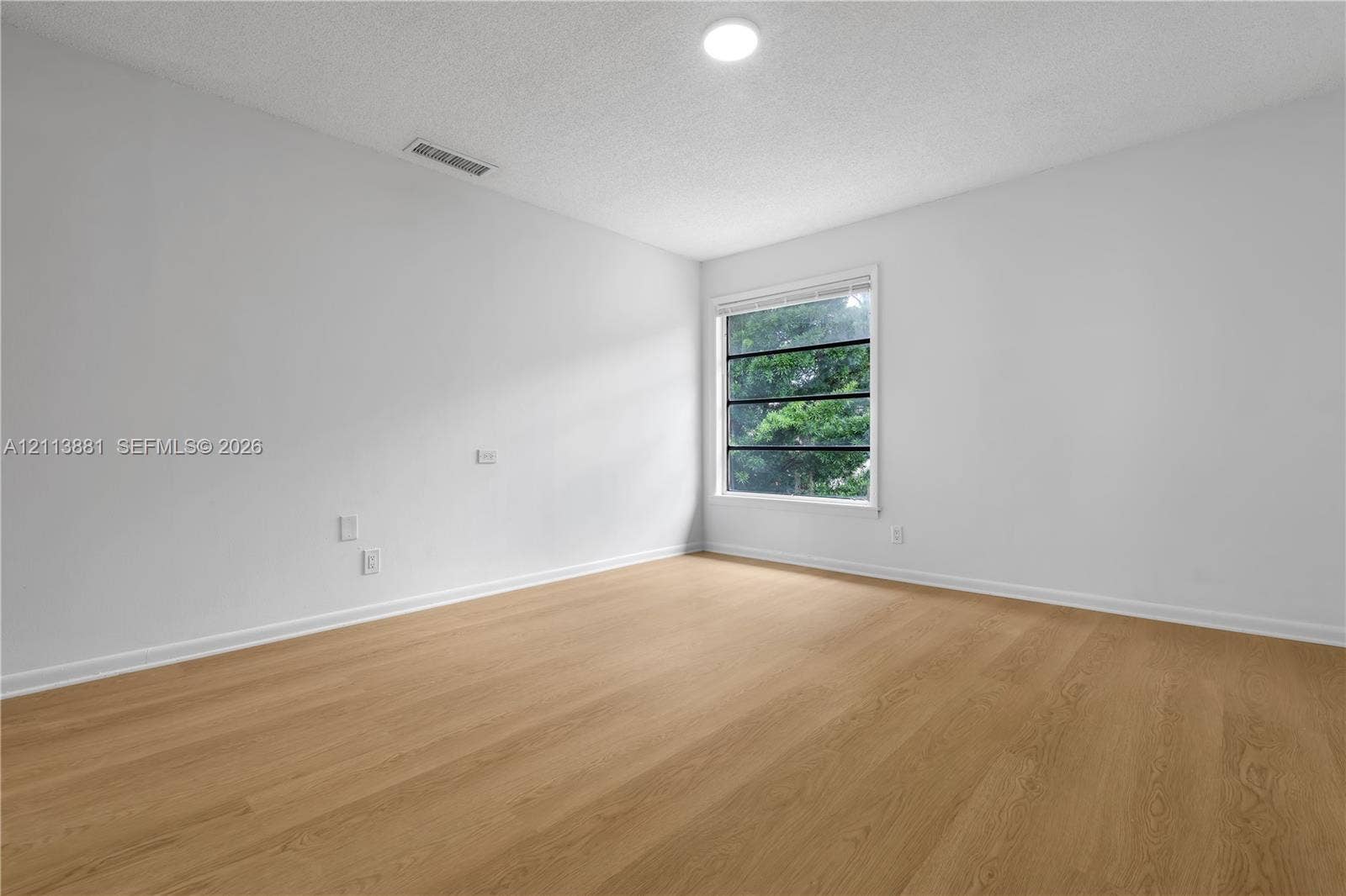 3886 Meadow Lane, #250, Hollywood, FL 33021 Room featuring wood-finish flooring, a single-pane window with dark frames, and a neutral color palette