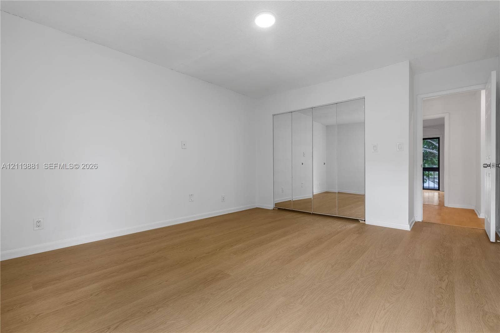 3886 Meadow Lane, #250, Hollywood, FL 33021 Neutral-toned interior featuring wood-finish flooring, white walls, and a built-in closet with mirrored sliding doors