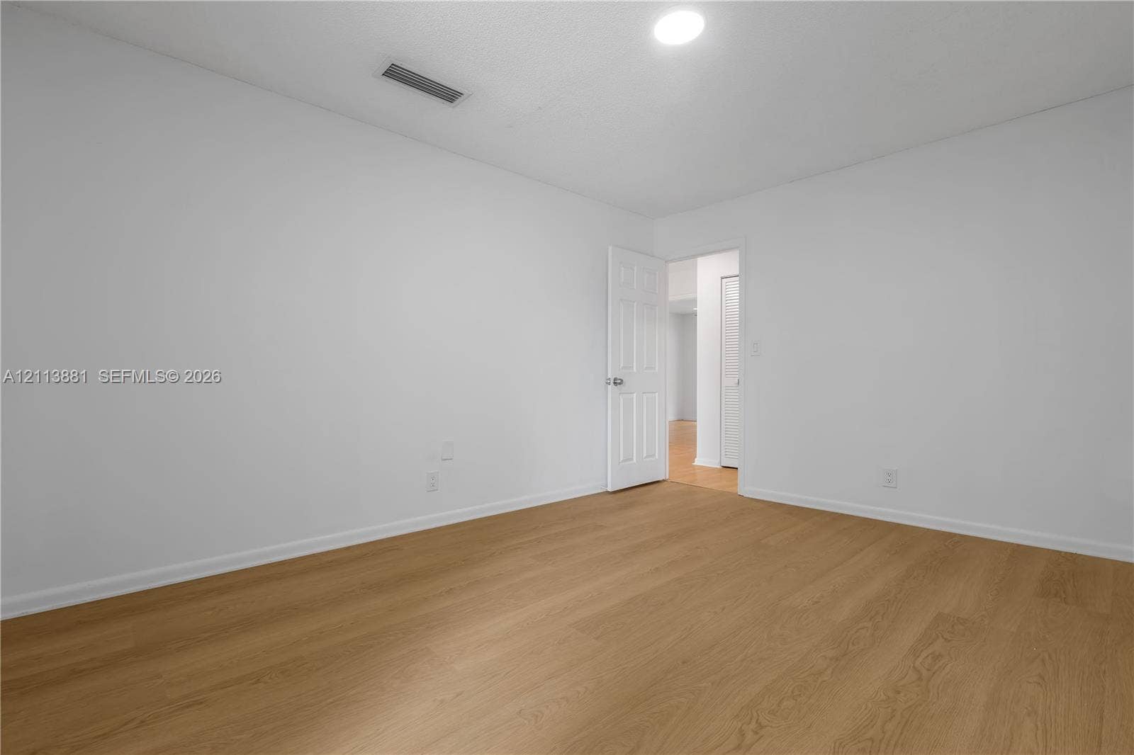 3886 Meadow Lane, #250, Hollywood, FL 33021 Neutral interior space featuring wood-finish flooring, white walls, and a multi-panel door