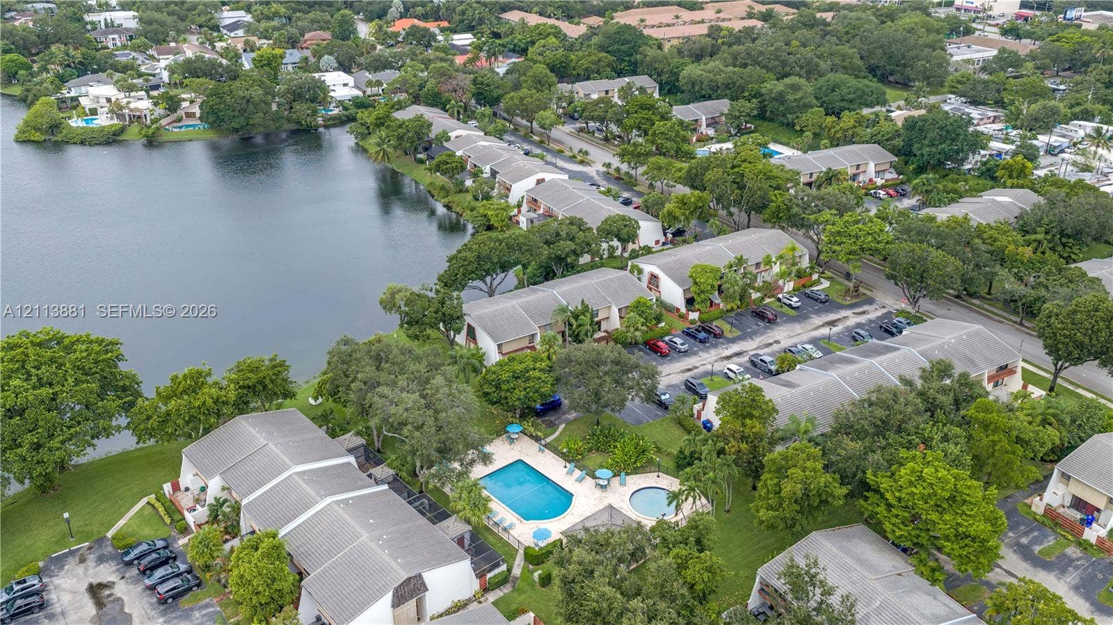 3886 Meadow Lane, #250, Hollywood, FL 33021 Aerial perspective featuring waterfront placement, community pool, spa, established landscaping, and paved parking