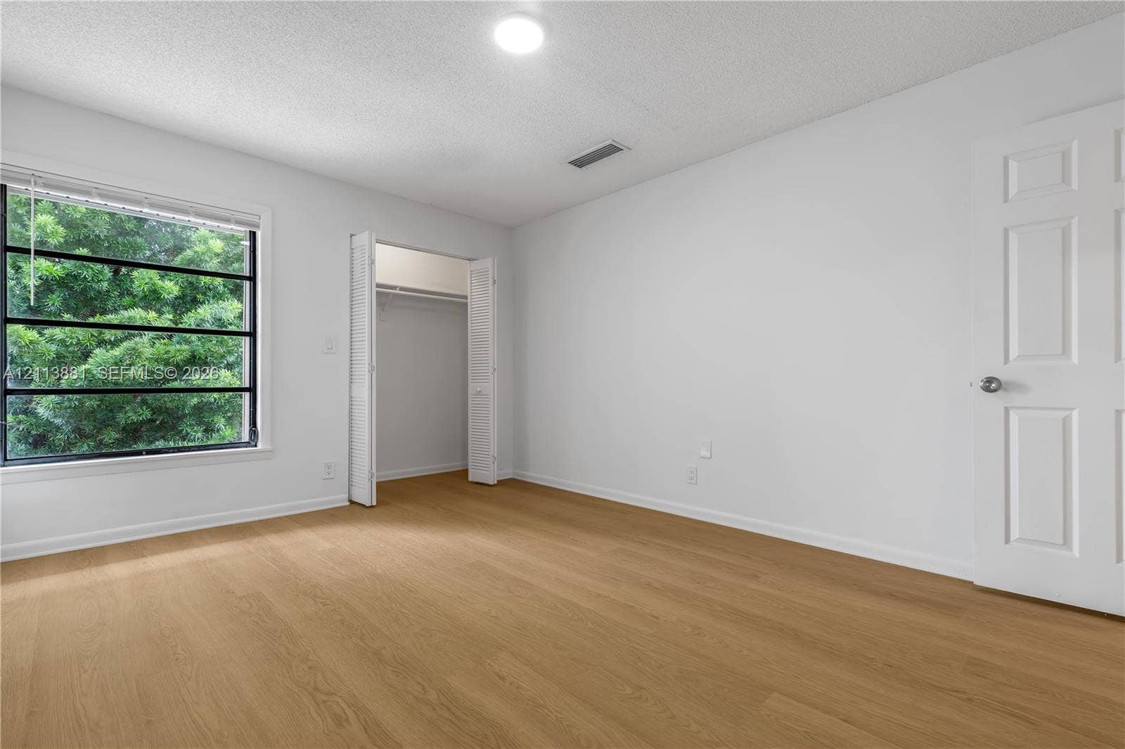 3886 Meadow Lane, #250, Hollywood, FL 33021 Wood-finish flooring, multi-pane window with exterior greenery, and bi-fold closet doors