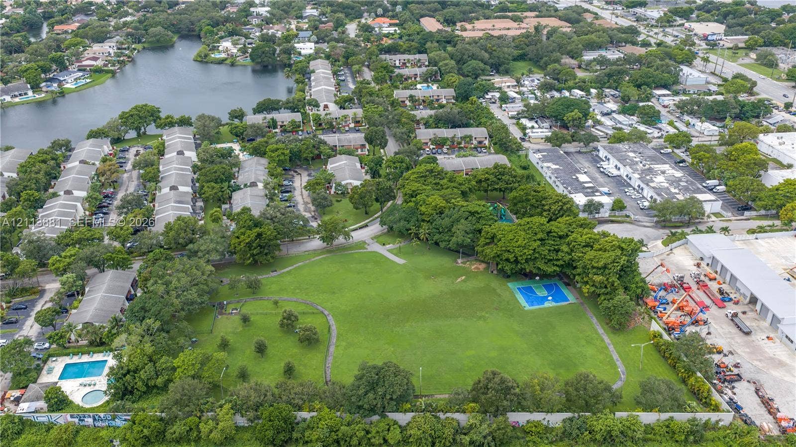 3886 Meadow Lane, #250, Hollywood, FL 33021 Aerial perspective featuring expansive green space, a basketball court, swimming pool, and mature trees