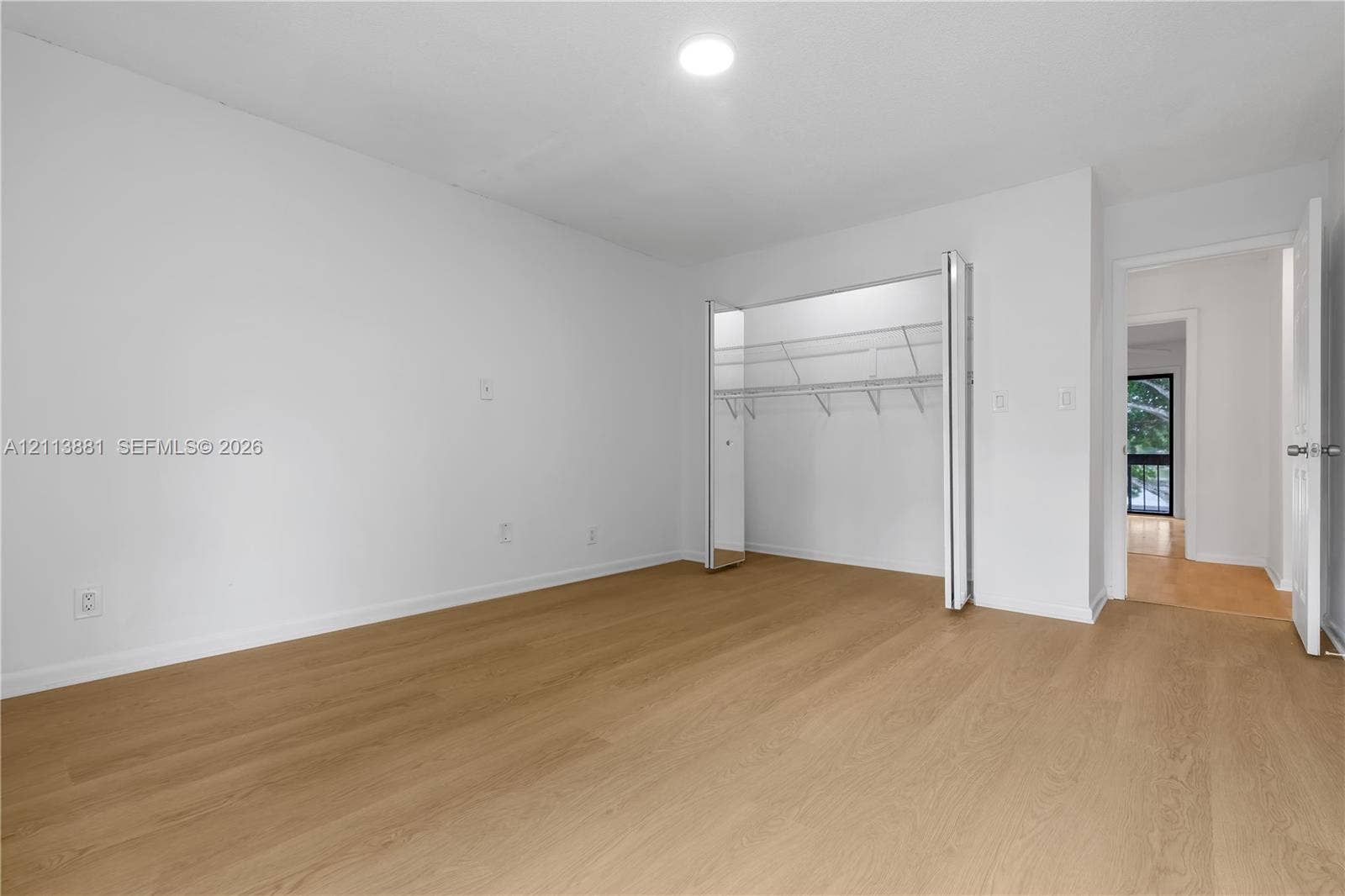 3886 Meadow Lane, #250, Hollywood, FL 33021 Neutral-toned interior featuring wood-finish flooring, white walls, flush-mount ceiling lighting, and a closet with bifold doors and wire shelving
